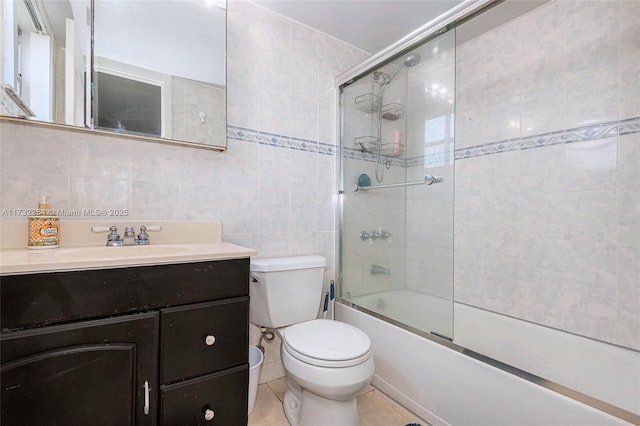 full bathroom featuring vanity, tile walls, shower / bath combination with glass door, and toilet