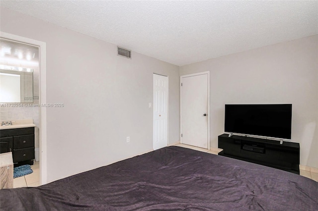 bedroom featuring sink, connected bathroom, a textured ceiling, and a closet