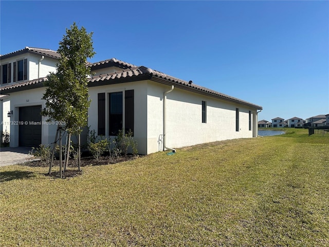 view of home's exterior featuring a garage, a tile roof, decorative driveway, a lawn, and stucco siding