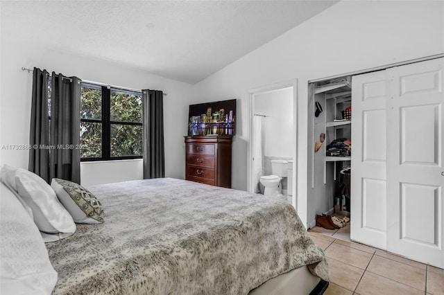 tiled bedroom with lofted ceiling, connected bathroom, and a closet