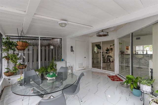 unfurnished sunroom featuring beam ceiling