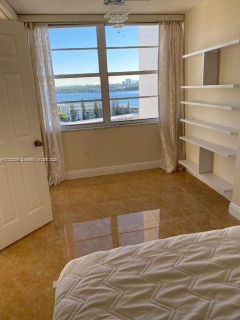 unfurnished bedroom featuring multiple windows, an inviting chandelier, and a water view