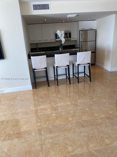 kitchen with appliances with stainless steel finishes, a breakfast bar, and sink