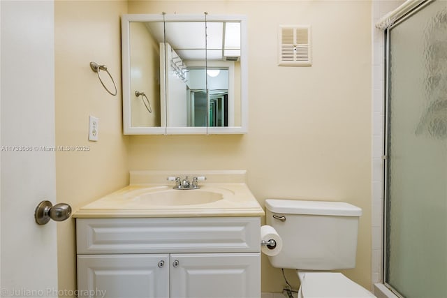 bathroom featuring vanity, toilet, and a shower with shower door