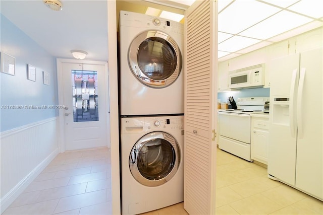 washroom with stacked washer / drying machine and light tile patterned floors