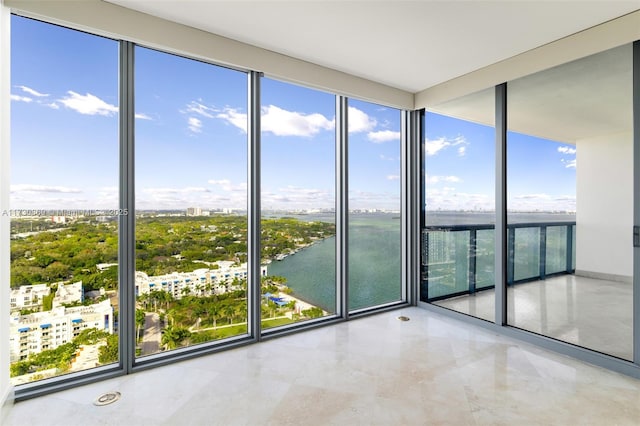 spare room featuring a water view, a wall of windows, and a city view