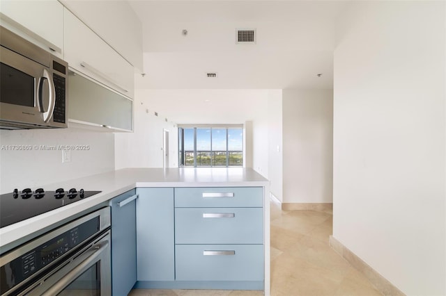 kitchen with light tile patterned floors, appliances with stainless steel finishes, visible vents, light countertops, and a peninsula