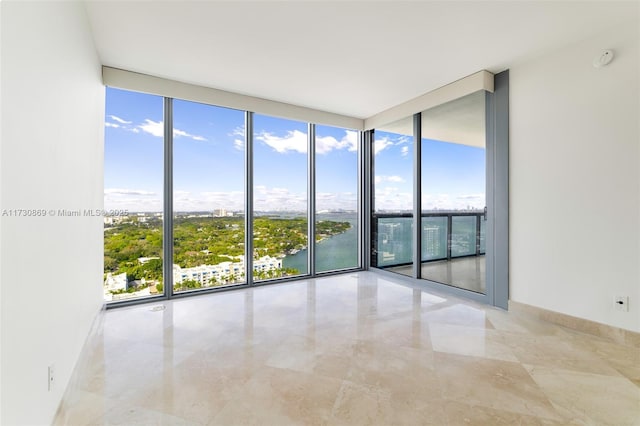 empty room featuring marble finish floor, floor to ceiling windows, and a wealth of natural light