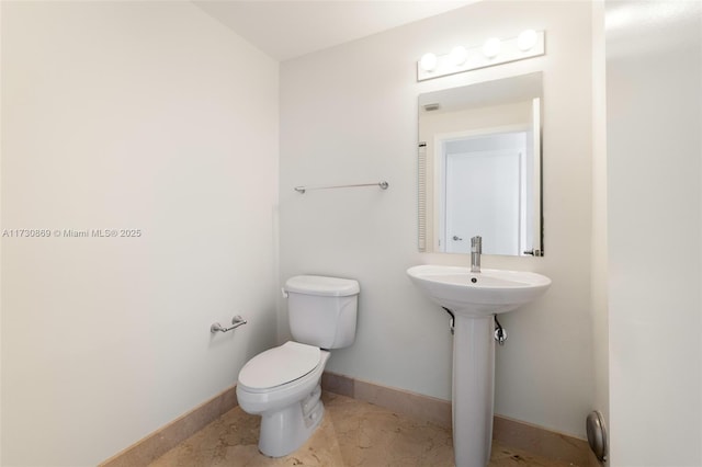 half bath featuring toilet and baseboards