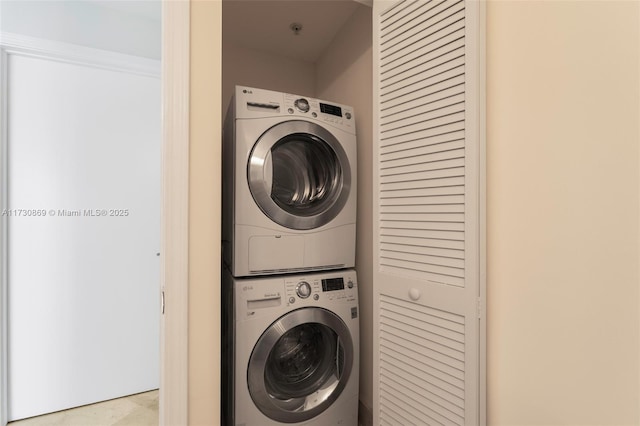 clothes washing area featuring stacked washer and clothes dryer and laundry area