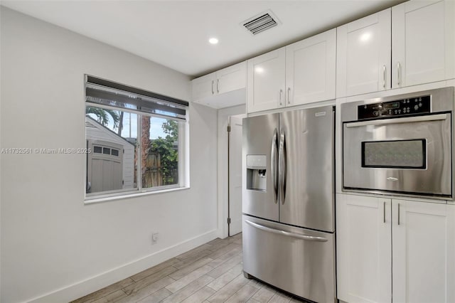 kitchen with light wood-type flooring, white cabinets, and appliances with stainless steel finishes