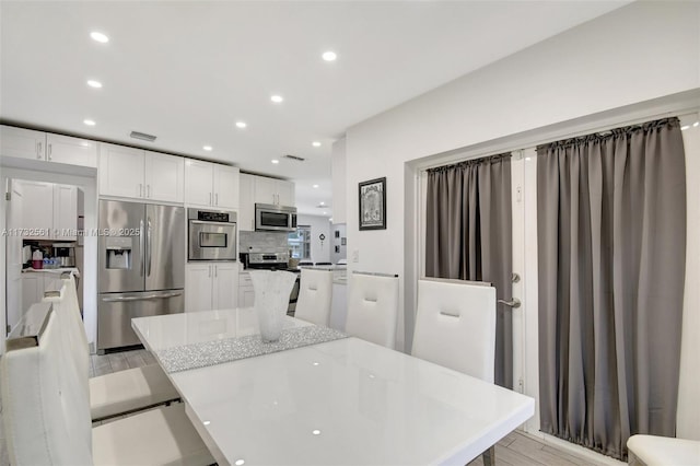 kitchen featuring backsplash, appliances with stainless steel finishes, light stone countertops, and white cabinets