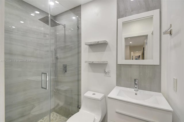 bathroom featuring vanity, a shower with shower door, and toilet