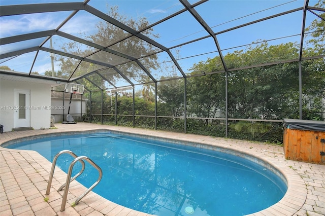 view of pool with a patio area, a hot tub, and glass enclosure