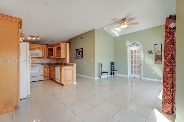 kitchen with sink, white appliances, vaulted ceiling, and light tile patterned flooring