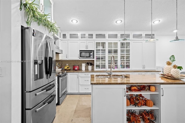 kitchen with sink, stainless steel appliances, hanging light fixtures, and dark stone counters