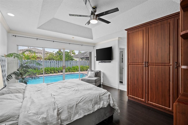 bedroom featuring ornamental molding, access to outside, ceiling fan, a tray ceiling, and dark wood-type flooring