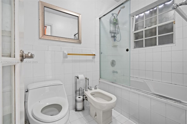 bathroom with toilet, bath / shower combo with glass door, tile walls, a bidet, and tile patterned flooring