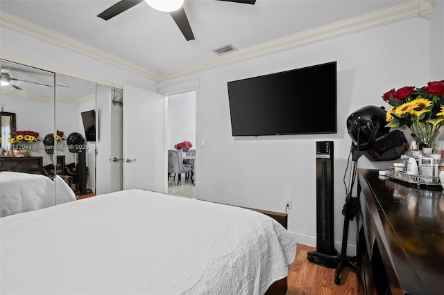 bedroom with wood-type flooring, crown molding, and ceiling fan