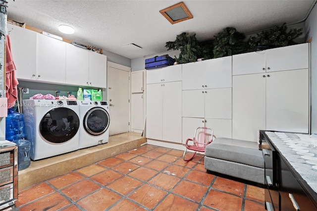 washroom with cabinets, washer and dryer, and a textured ceiling