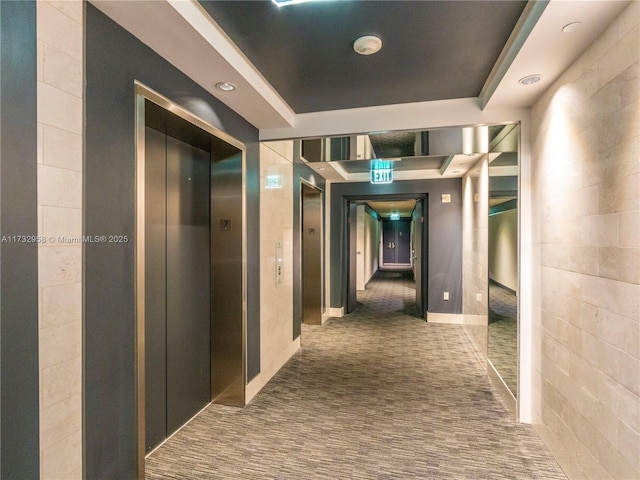 hallway featuring a raised ceiling, carpet flooring, and elevator