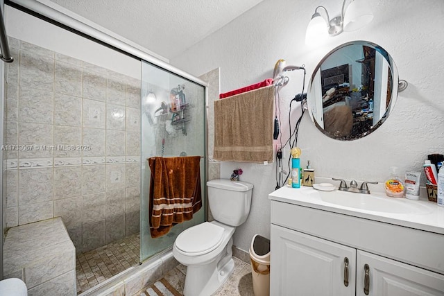 bathroom with vanity, toilet, a shower with door, and a textured ceiling