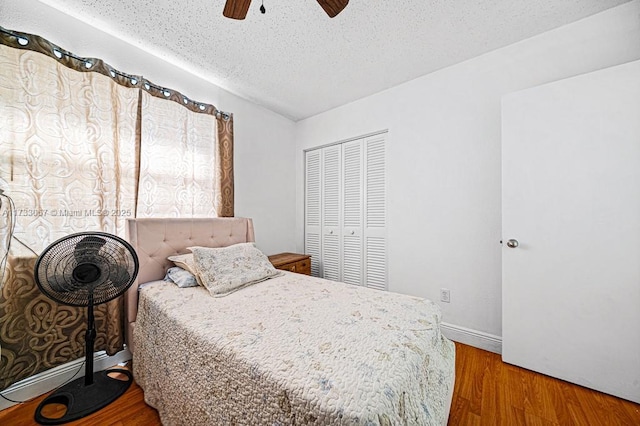 bedroom featuring hardwood / wood-style flooring, a textured ceiling, ceiling fan, and a closet