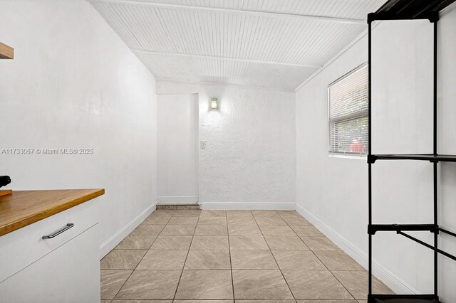 interior space featuring wood counters, tasteful backsplash, sink, white cabinets, and light tile patterned floors