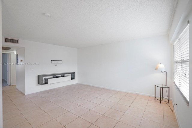 unfurnished living room with a wealth of natural light, a textured ceiling, and light tile patterned floors