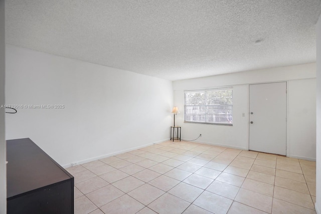 unfurnished room with a textured ceiling and light tile patterned flooring