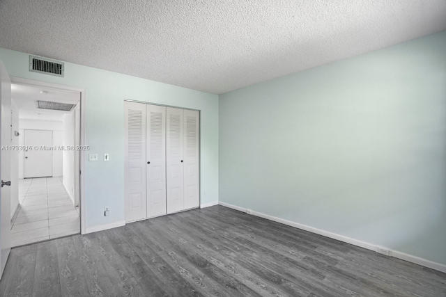 unfurnished bedroom with a closet, dark hardwood / wood-style flooring, and a textured ceiling