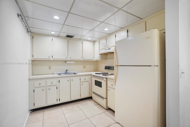 kitchen with a paneled ceiling, sink, white cabinets, light tile patterned floors, and white appliances