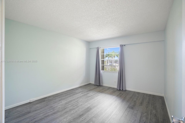 spare room with dark hardwood / wood-style floors and a textured ceiling