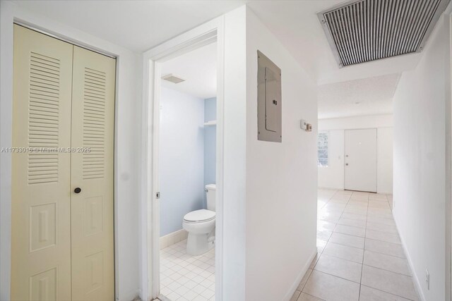 hall with light tile patterned flooring and electric panel