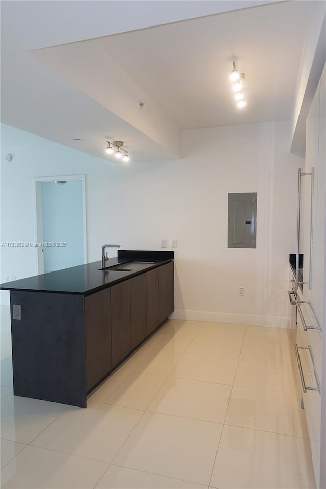 kitchen featuring dark brown cabinetry, light tile patterned floors, electric panel, and sink