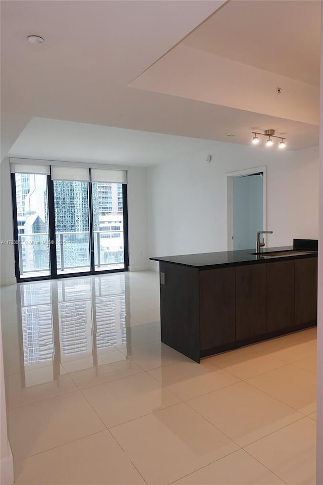 kitchen featuring sink, light tile patterned floors, and dark brown cabinetry