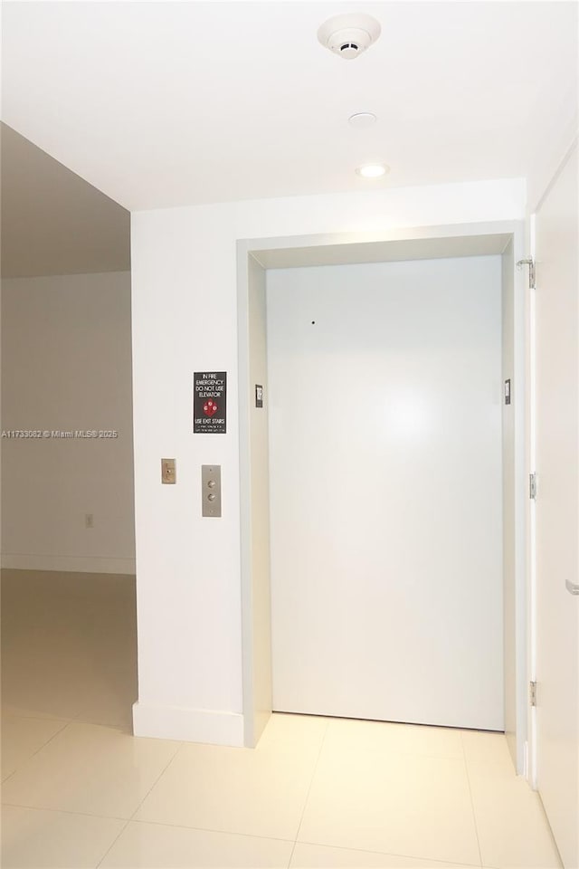 hall with elevator and light tile patterned floors