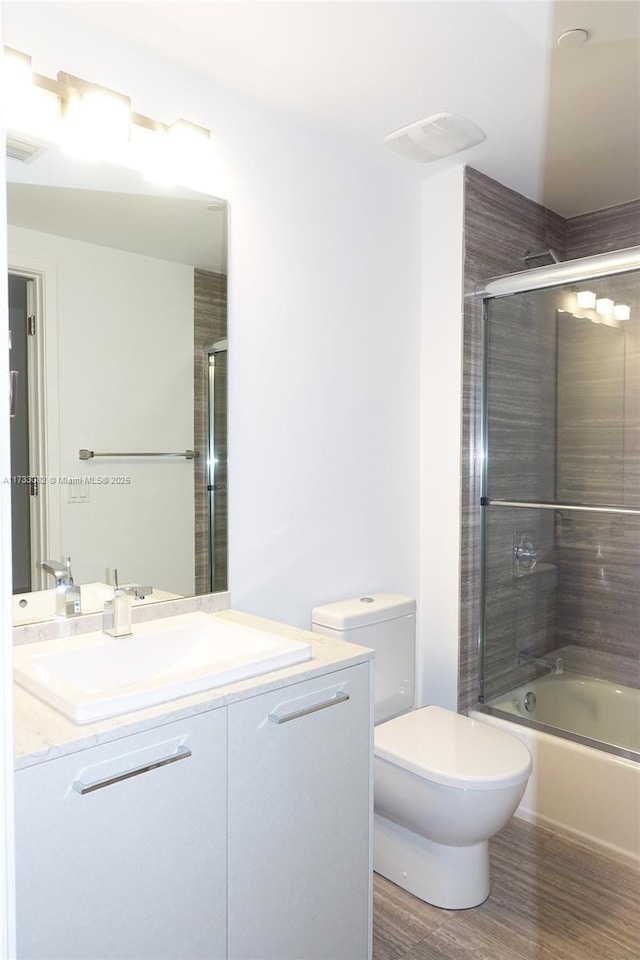 full bathroom with vanity, toilet, combined bath / shower with glass door, and wood-type flooring