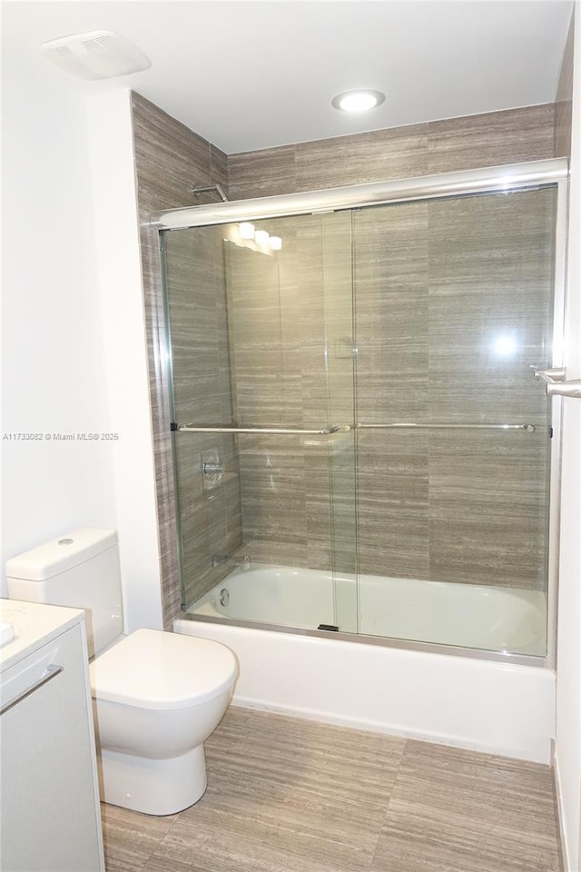 full bathroom featuring vanity, enclosed tub / shower combo, and toilet