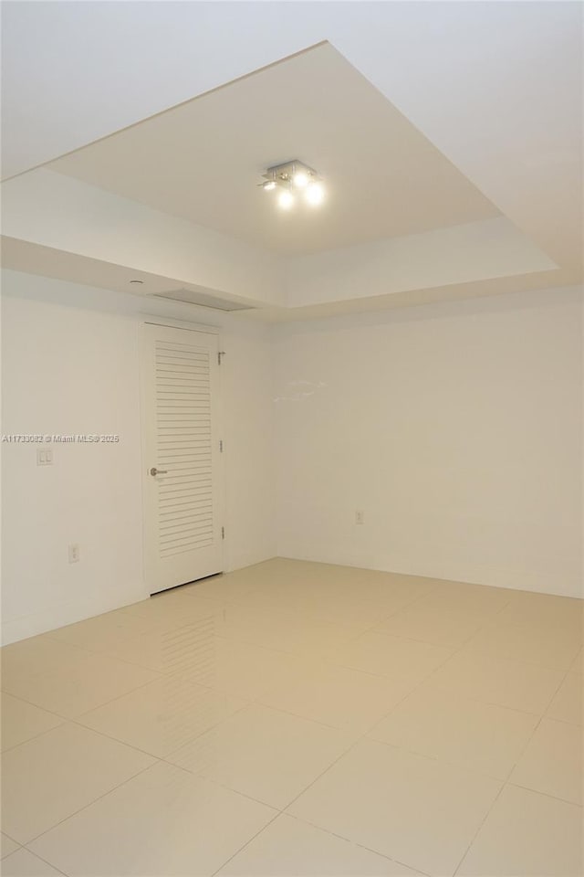 spare room with tile patterned floors and a tray ceiling