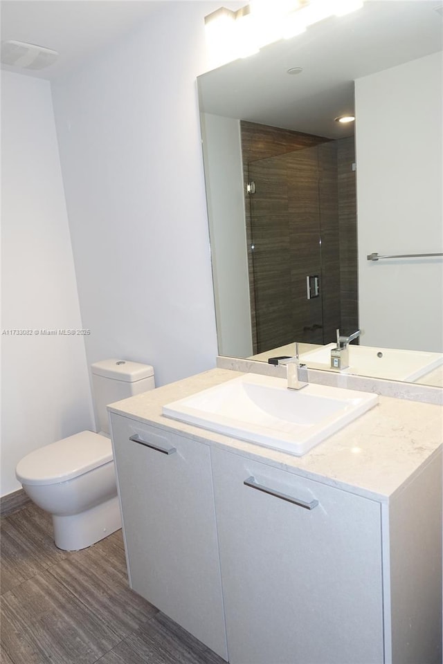 bathroom featuring walk in shower, vanity, toilet, and wood-type flooring