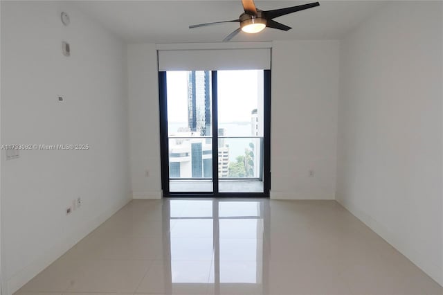 unfurnished room with light tile patterned flooring, ceiling fan, plenty of natural light, and floor to ceiling windows