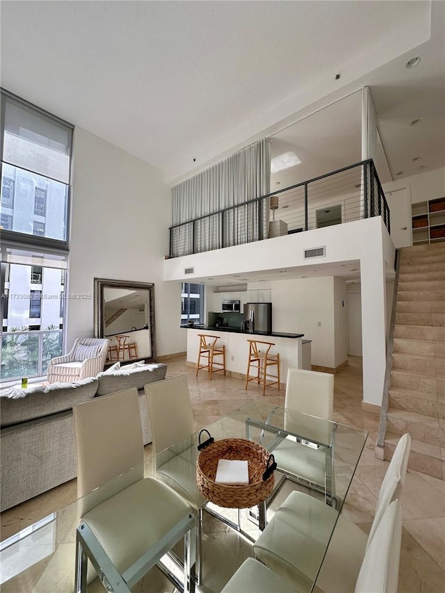 dining room with a towering ceiling and light tile patterned floors