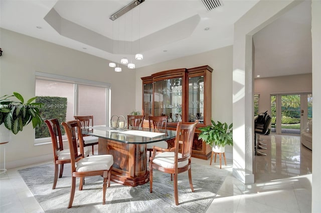 tiled dining space featuring a towering ceiling and a tray ceiling