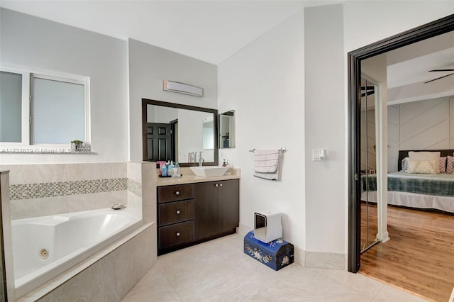 bedroom with a tray ceiling, light hardwood / wood-style floors, ceiling fan, and ensuite bathroom