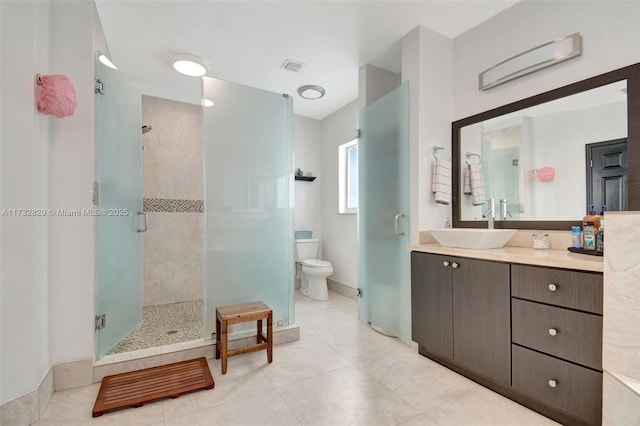 bathroom featuring a shower with door, vanity, tile patterned flooring, and toilet