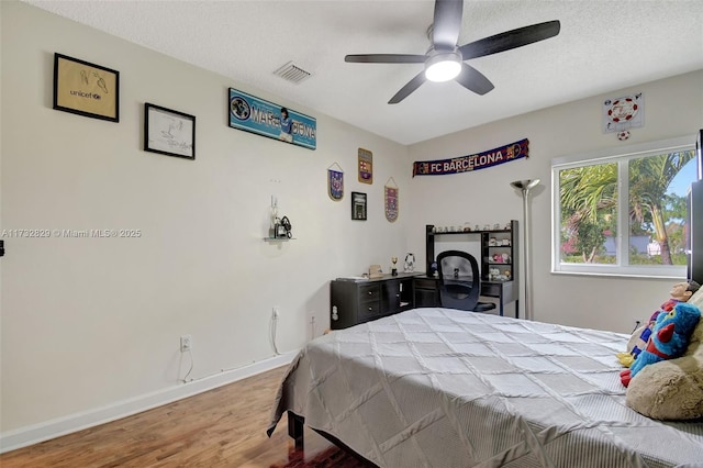 bedroom with ceiling fan, a textured ceiling, and light wood-type flooring