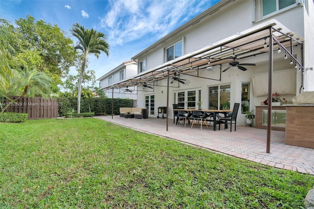 back of house with a lawn, ceiling fan, a patio area, an outdoor hangout area, and exterior kitchen