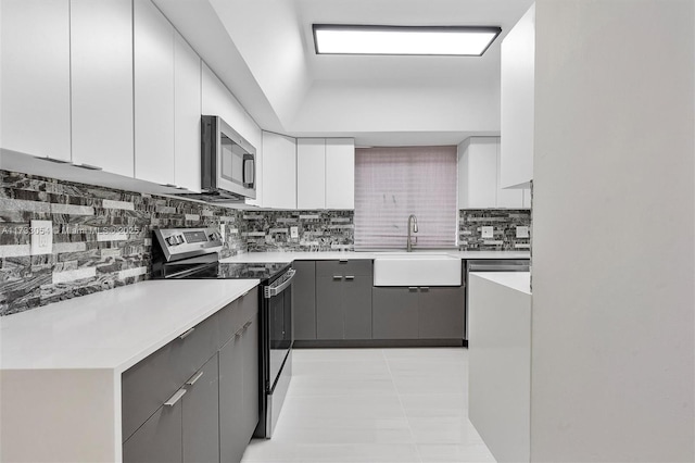 kitchen with gray cabinets, appliances with stainless steel finishes, sink, white cabinets, and light tile patterned floors