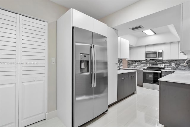 kitchen featuring light tile patterned flooring, tasteful backsplash, white cabinetry, sink, and stainless steel appliances